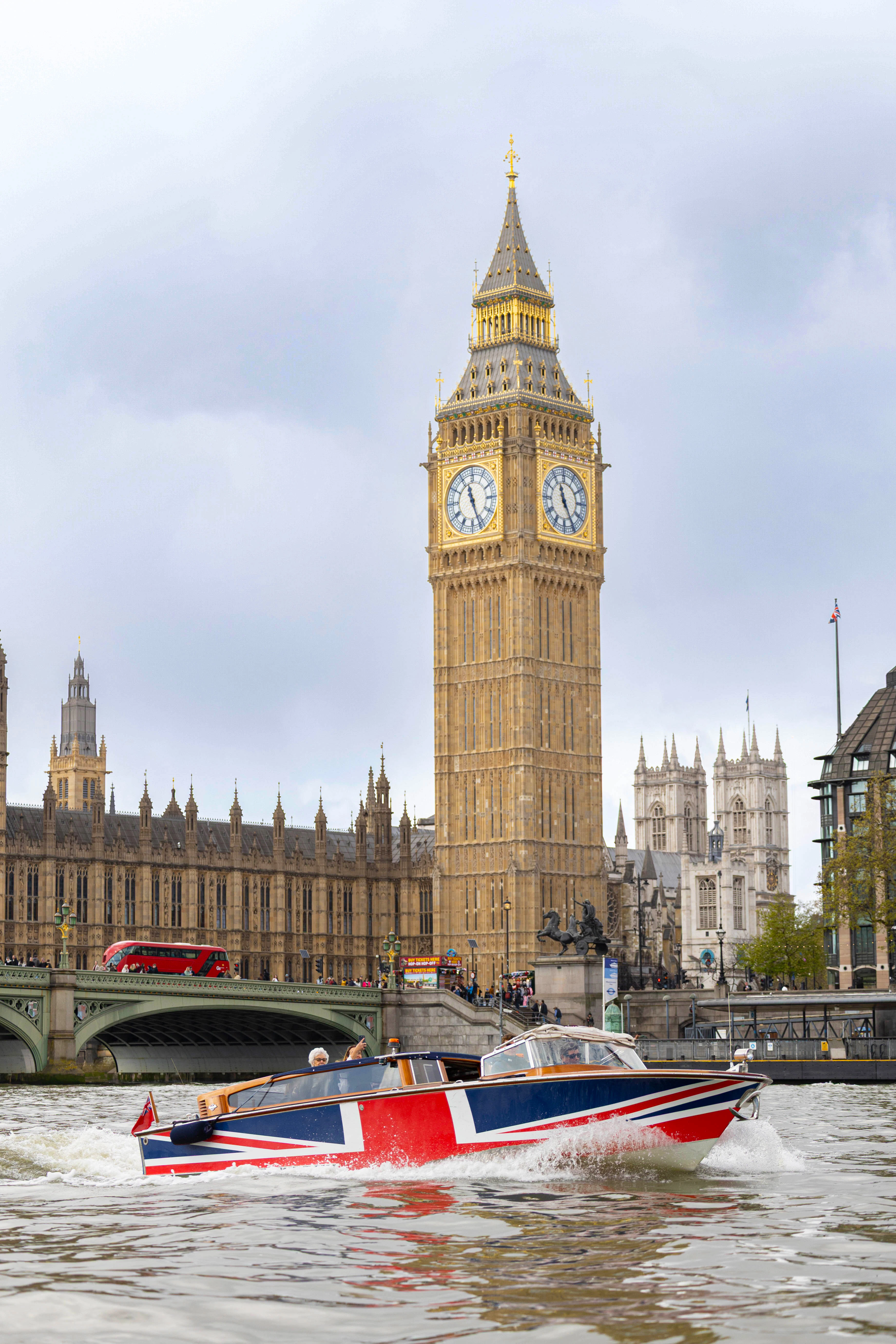 A Venetian-style boat adorned with the Union Flag sailing on the River Thames, with Big Ben in the background.