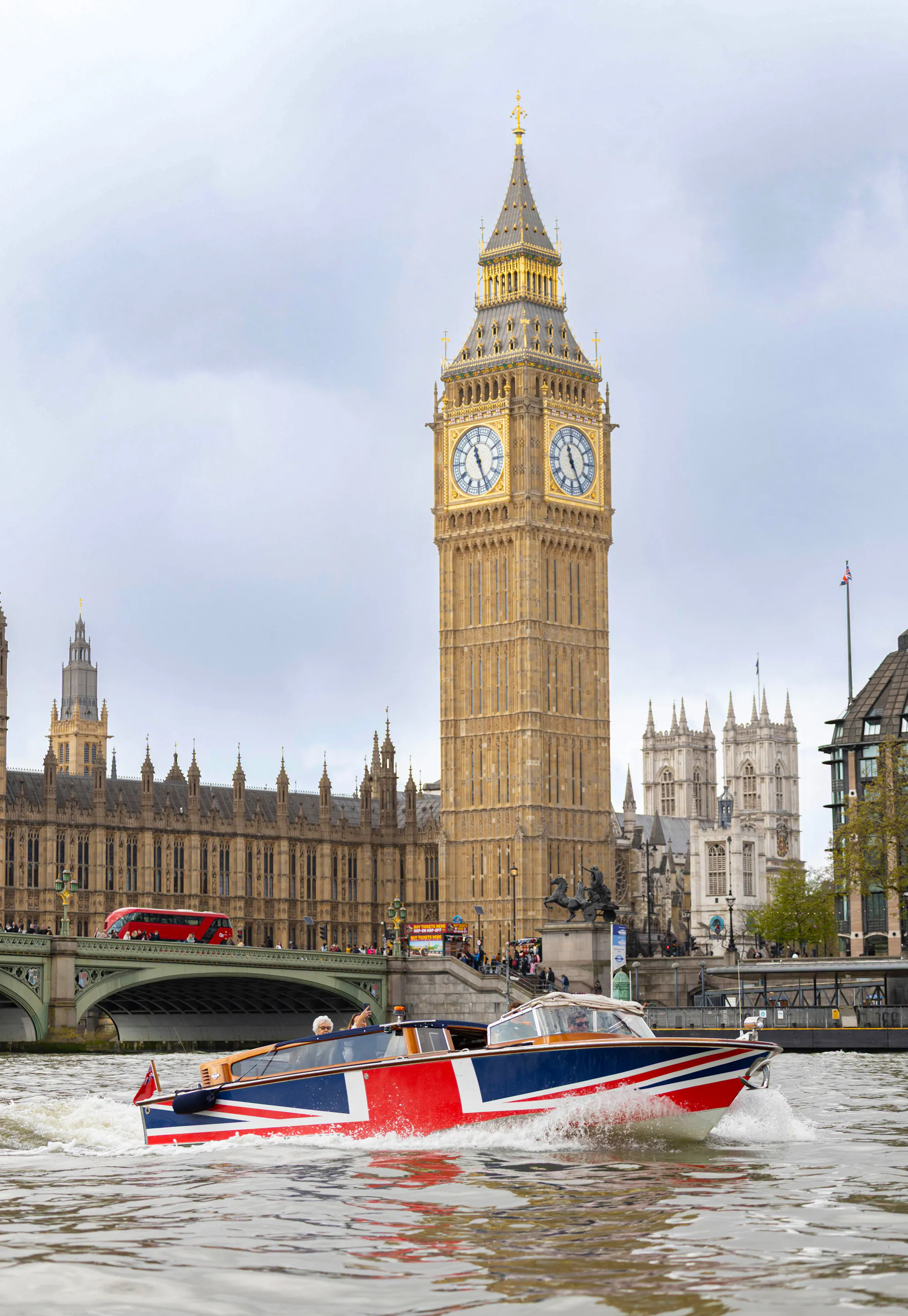 A Venetian-style boat adorned with the Union Flag sailing on the River Thames, with Big Ben in the background.