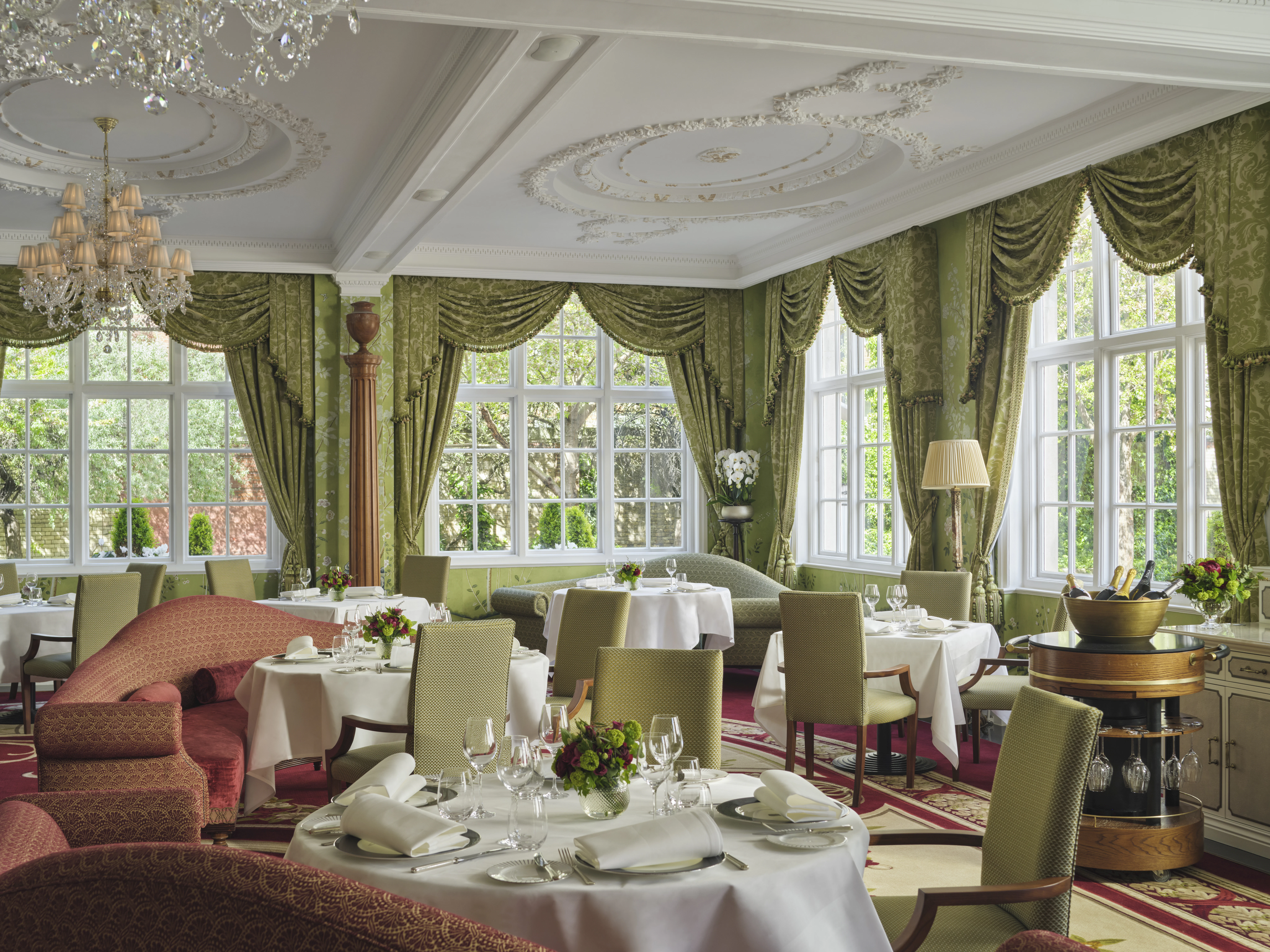 Tables set for lunch in The Goring's Dining Room, framed by sage-green drapes and garden-view windows.