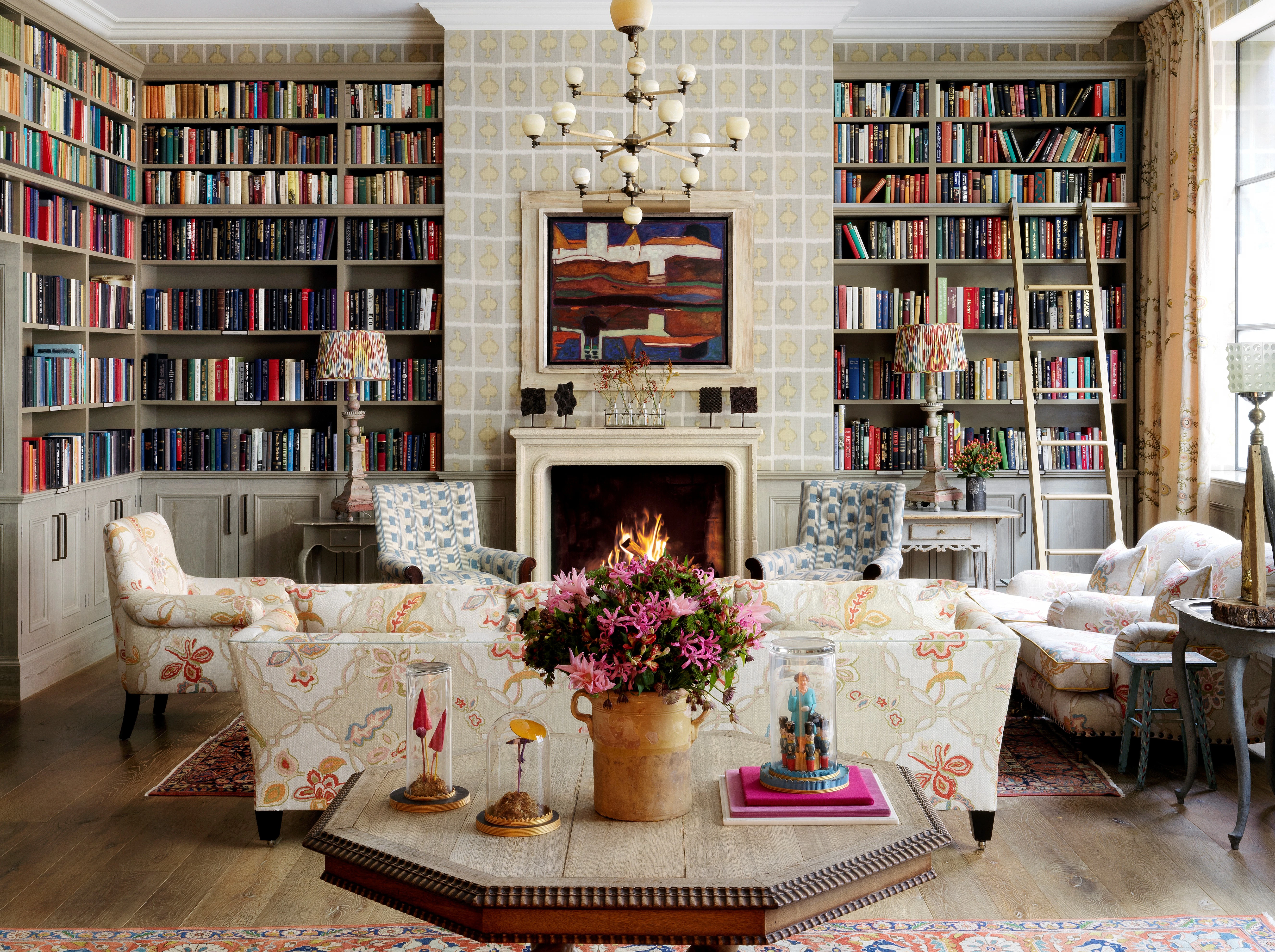 The Library at Ham Yard Hotel, with colourful book-lined shelves and a lit fireplace beside armchairs.