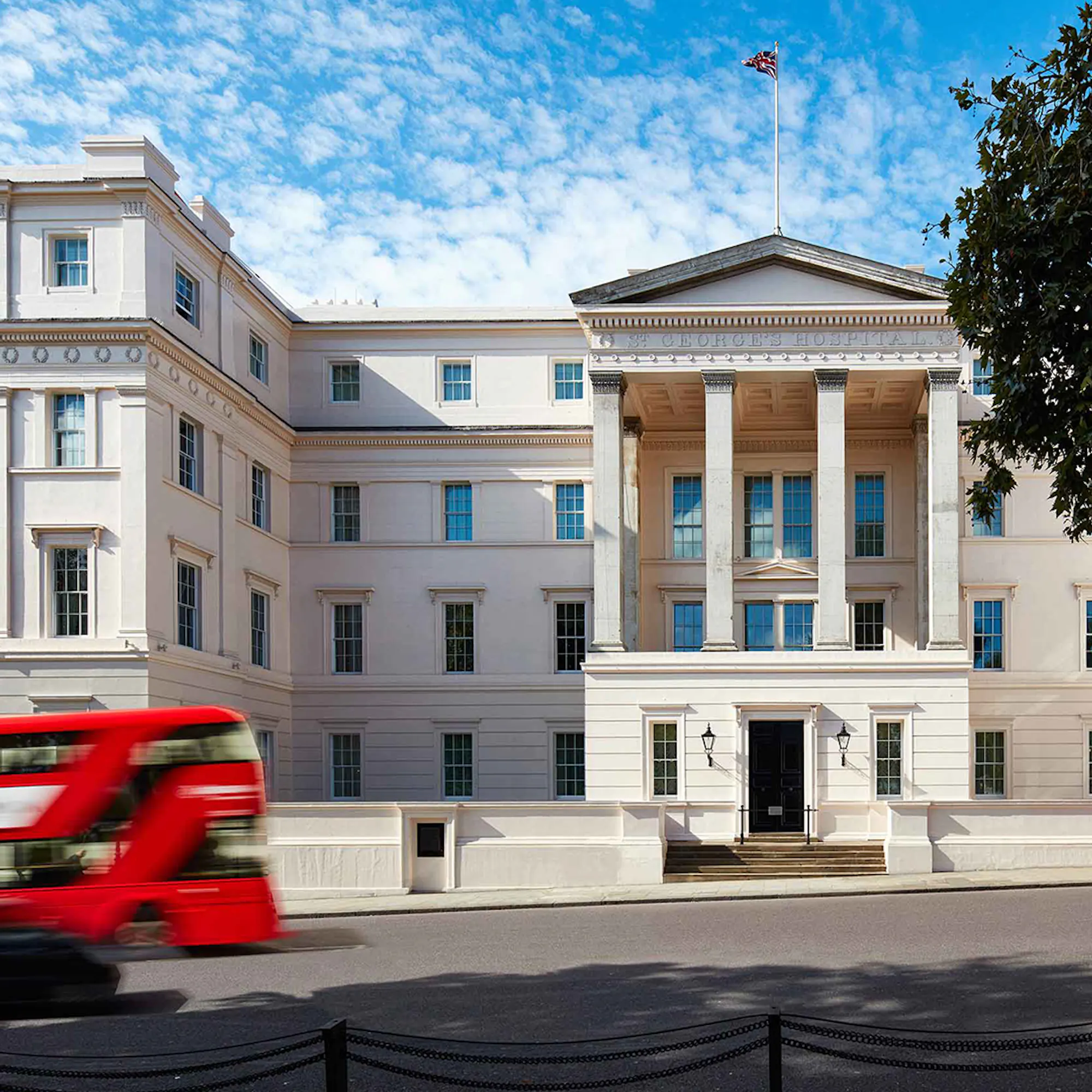 Front entrance of The Lanesborough Hotel with a red double-decker speeding past.