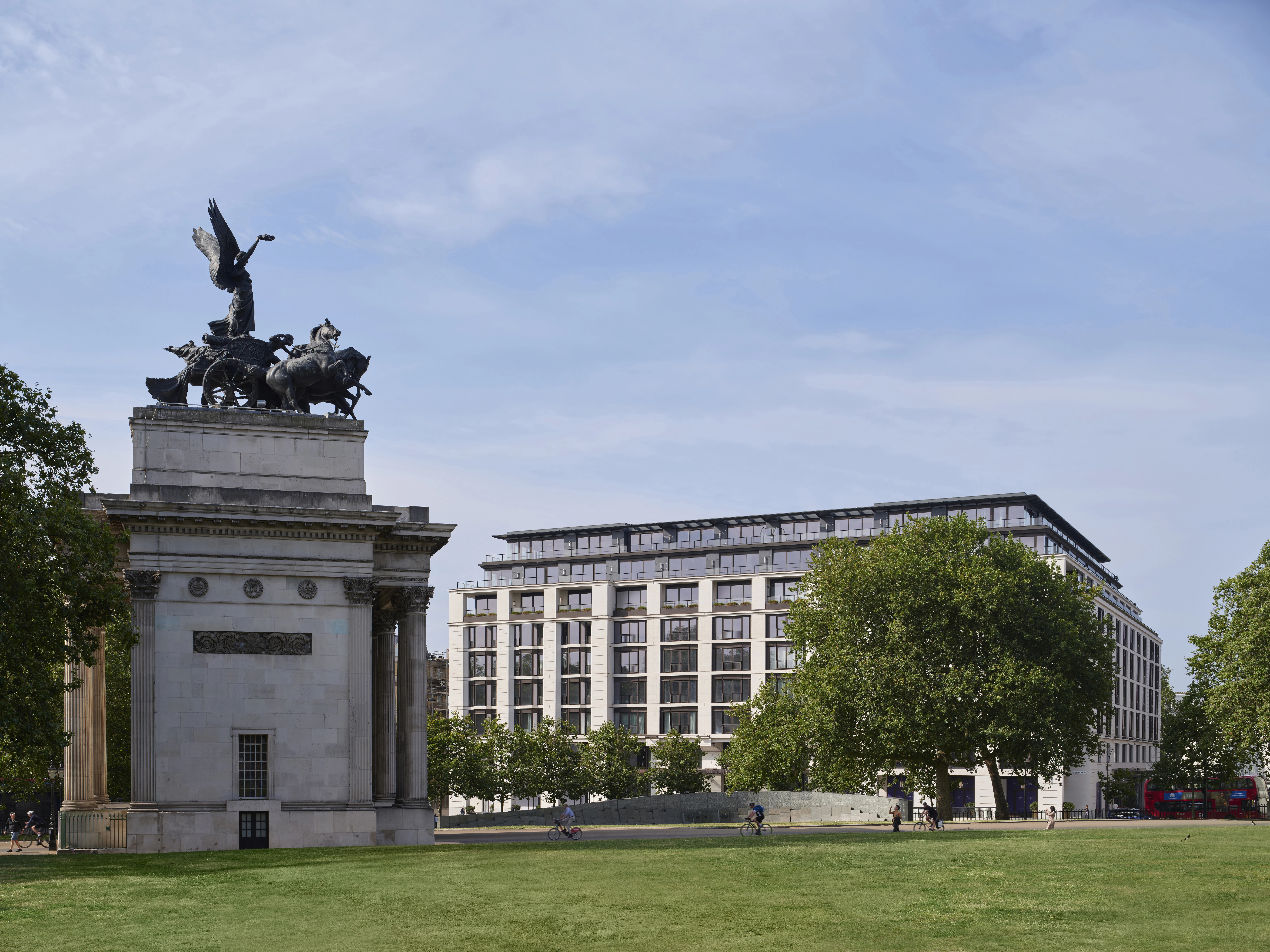 Wellington Arch's bronze Quadriga sculpture stands before The Peninsula London, across a green lawn.