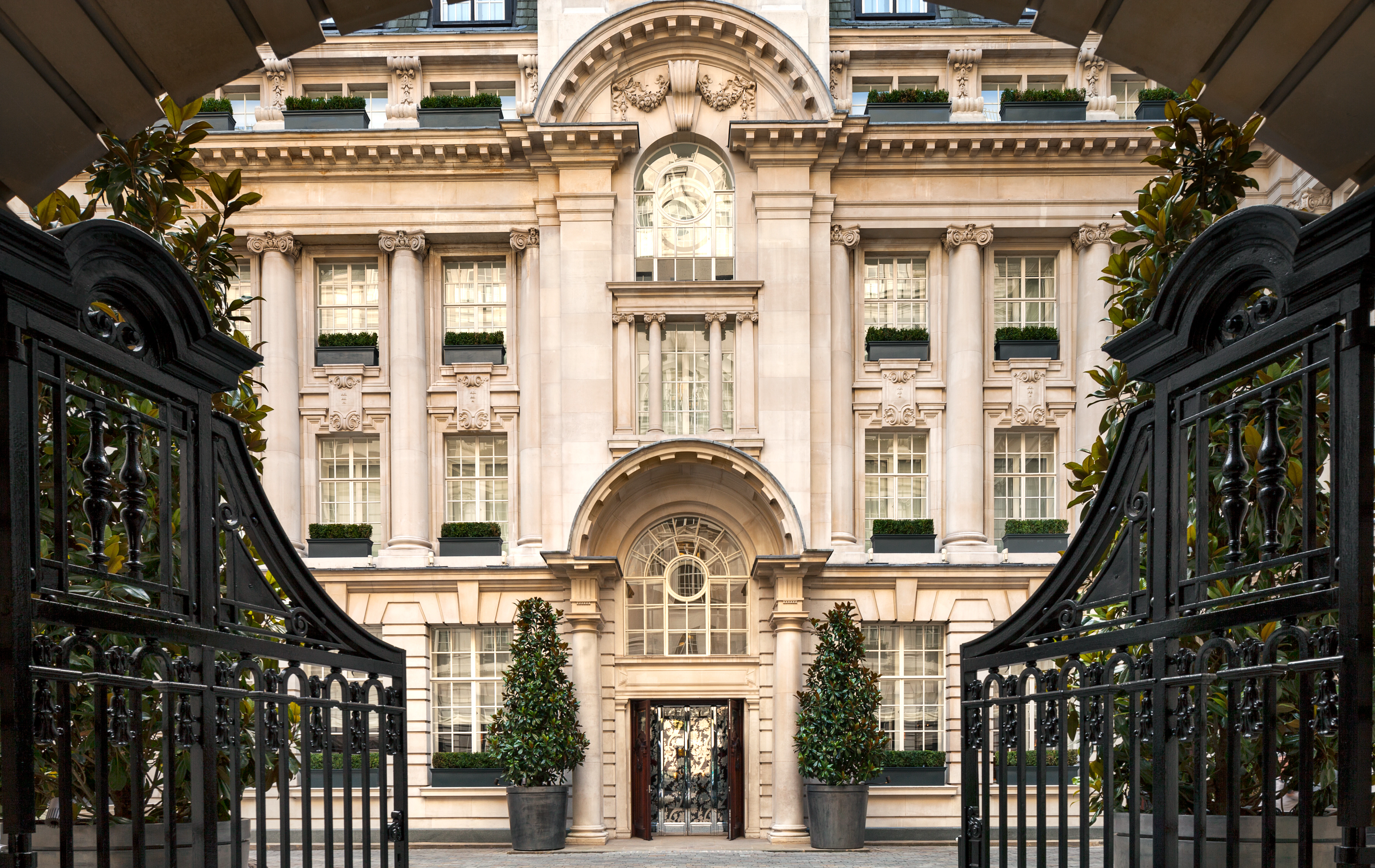 Rosewood London's stone facade, framed through its open iron gate.