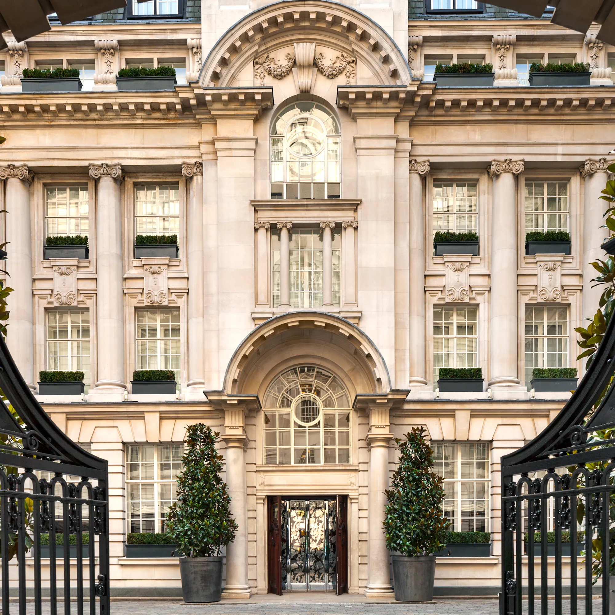 Rosewood London's stone facade, framed through its open iron gate.