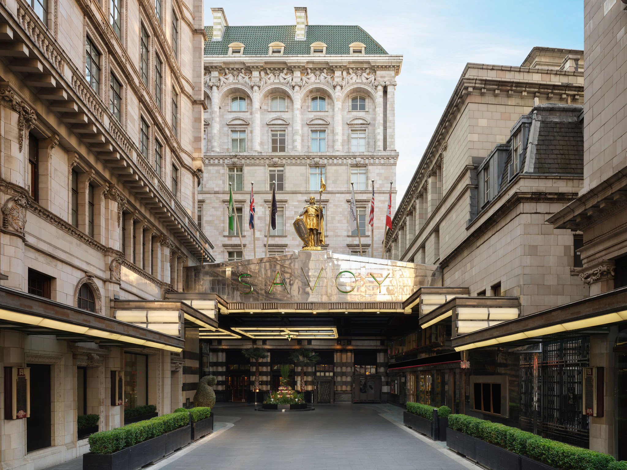 The gilded Savoy sign and knight statue above The Savoy's Strand forecourt, catching the light.