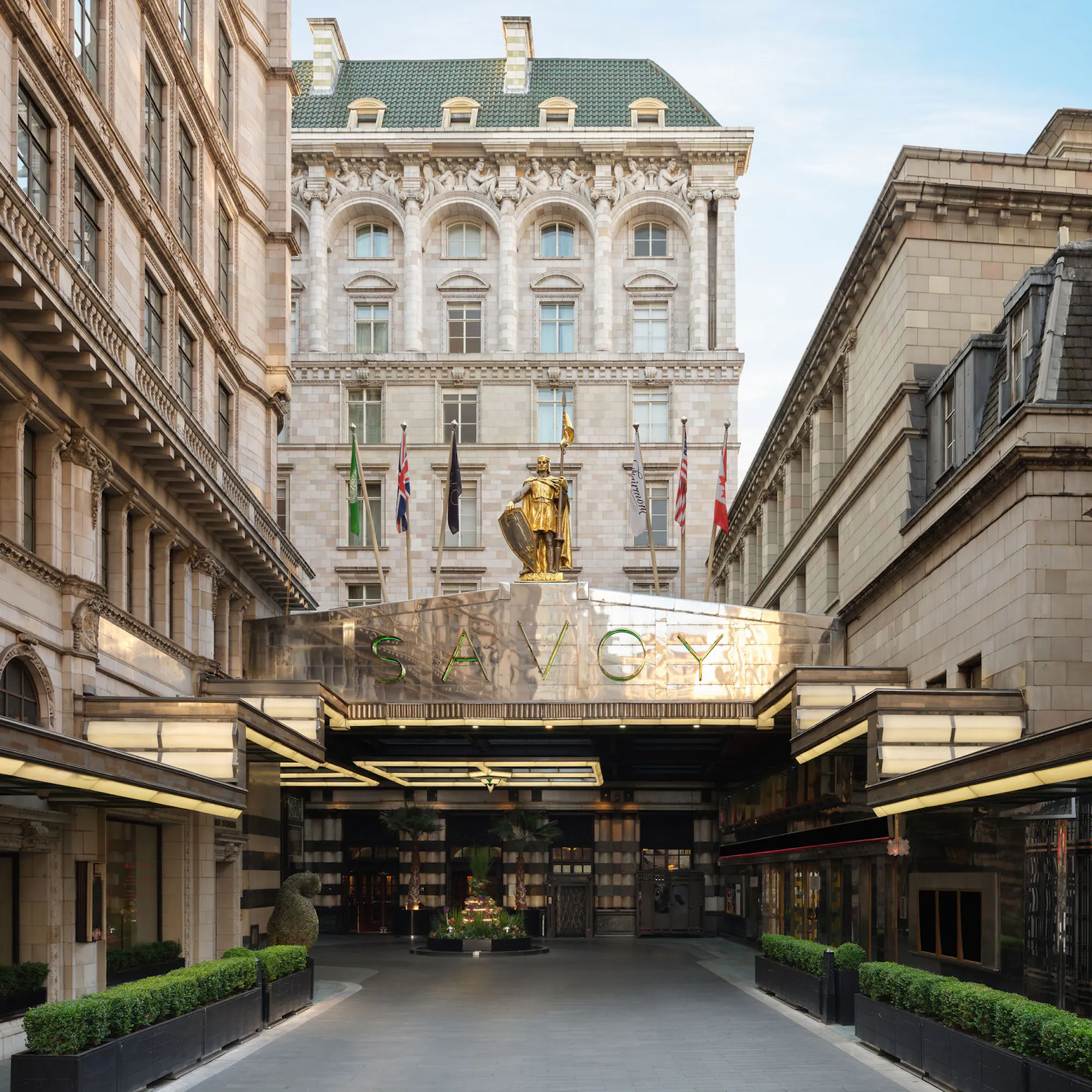 The gilded Savoy sign and knight statue above The Savoy's Strand forecourt, catching the light.