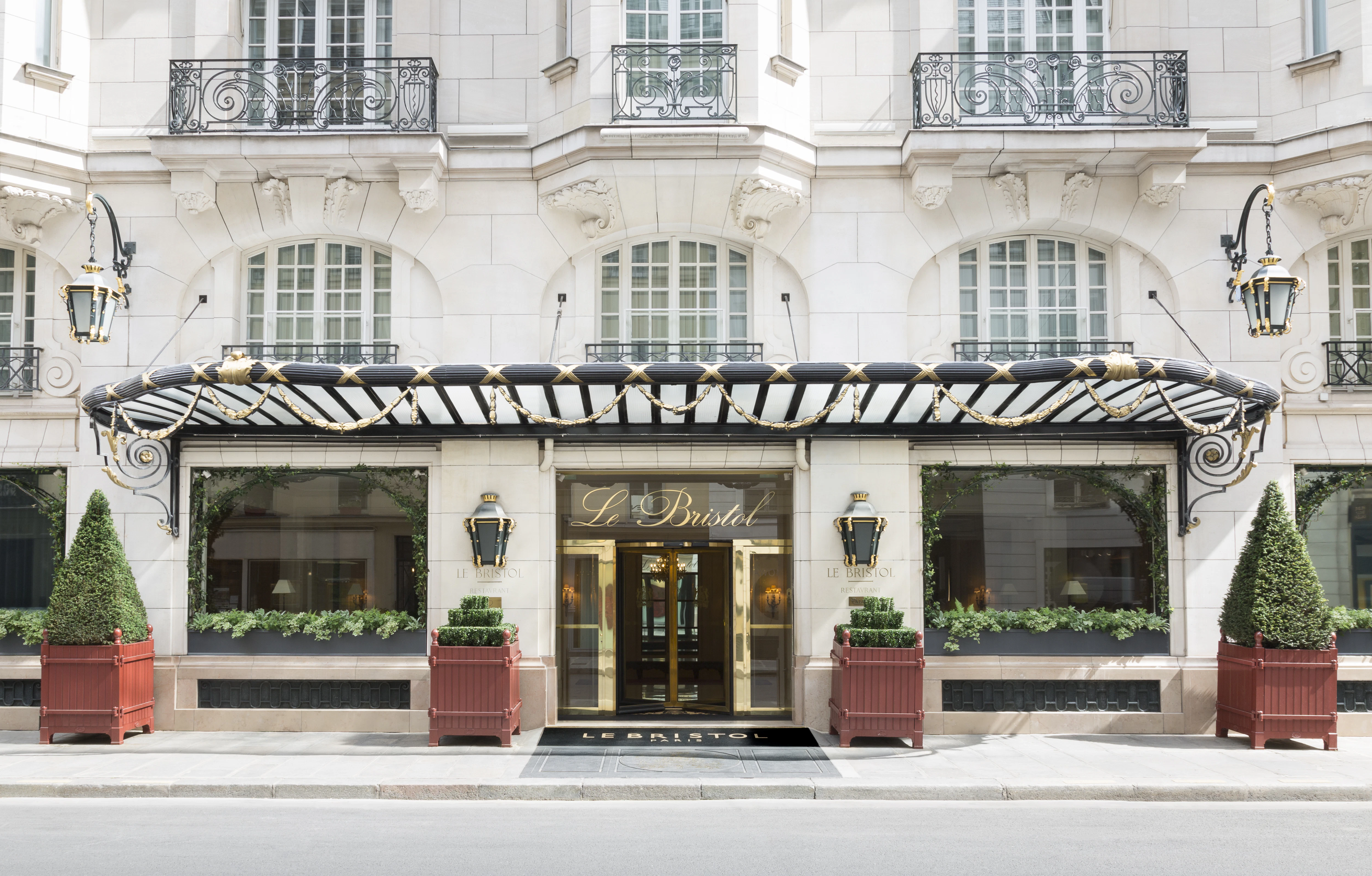 Le Bristol Paris's entrance, sun on the white stone facade and gilded doors.