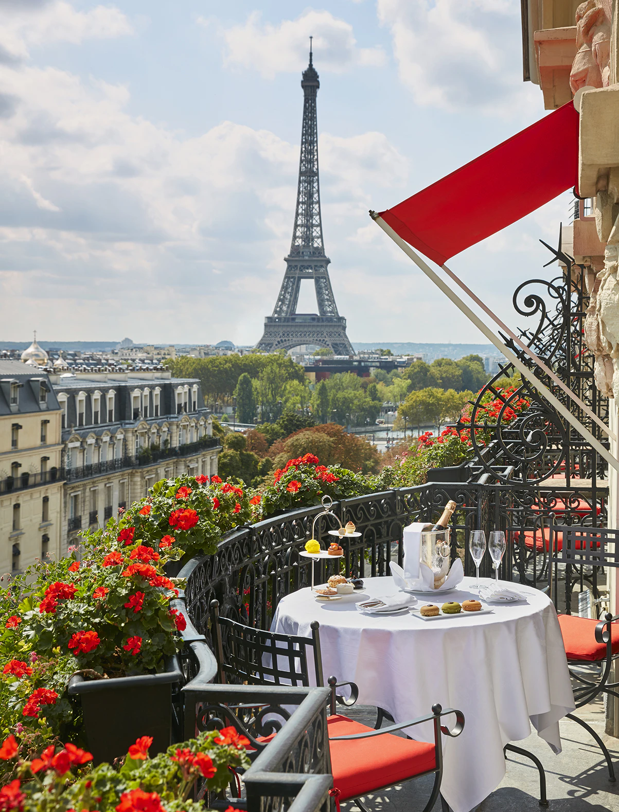 The Eiffel Tower from a balcony at Hôtel Plaza Athénée, with red awnings and geranium-filled window boxes.