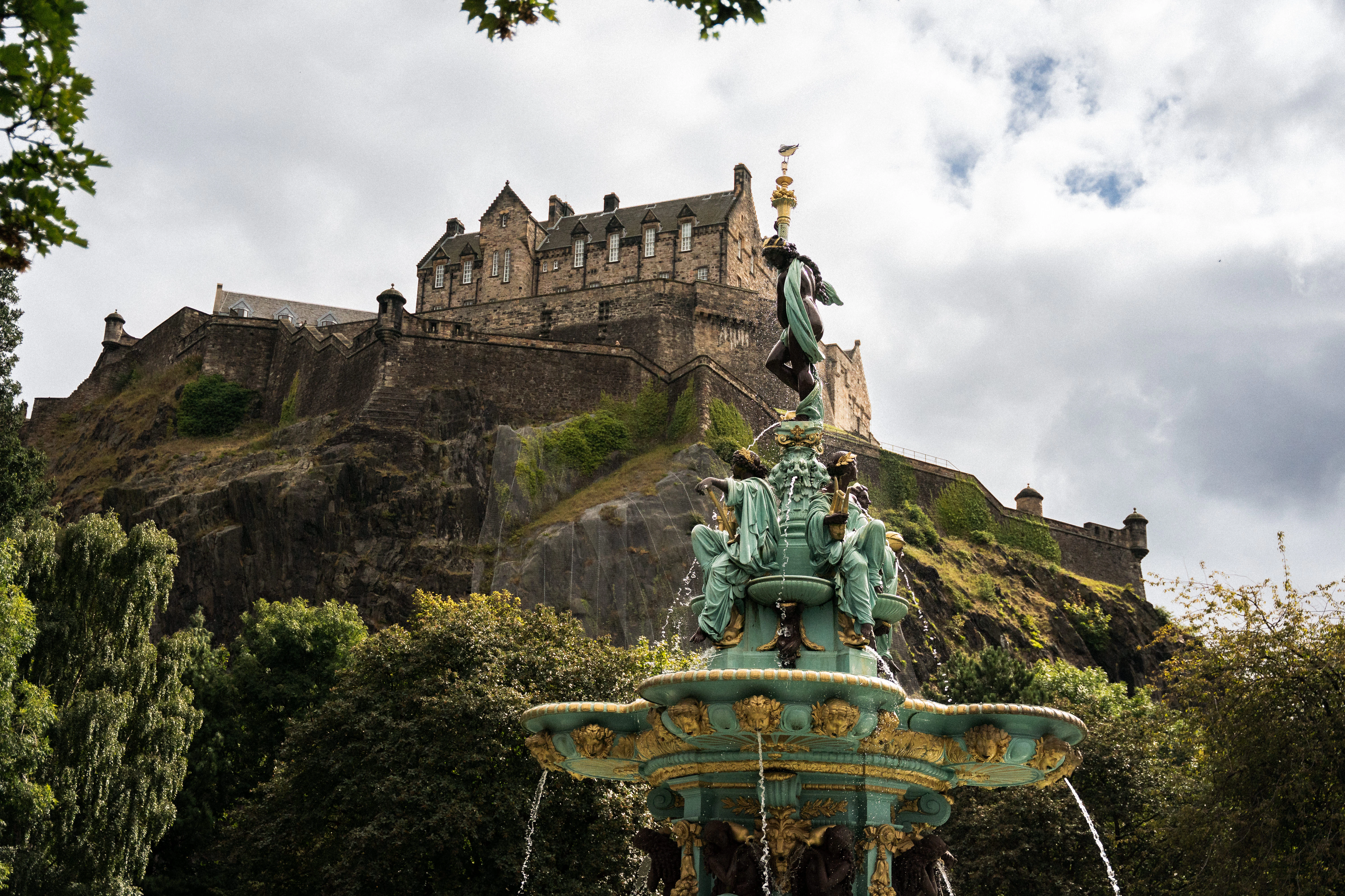 Edinburgh Castle atop its volcanic rock, seen past the ornate figures of the Ross Fountain.